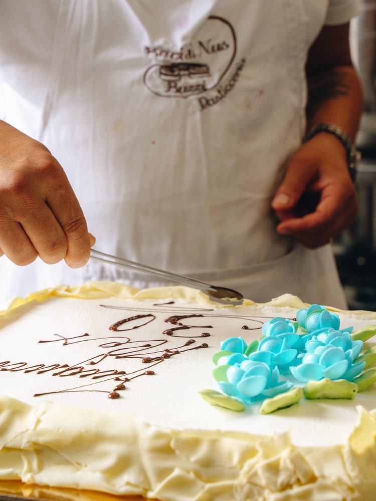 La scritta di auguri viene tracciata a mano sulla torta